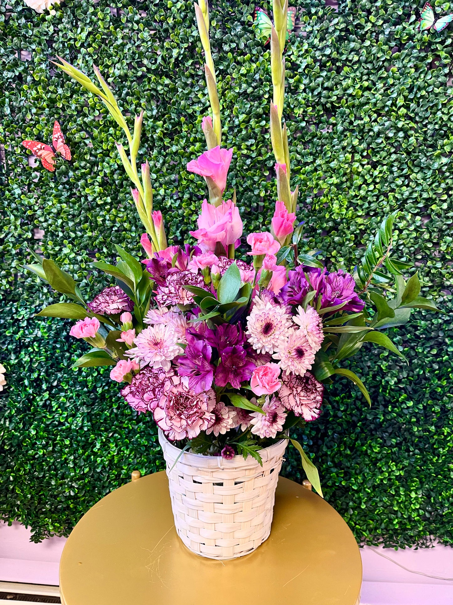 A sympathy floral basket arrangement with a variety of flowers in shades of pink, purple, and white.