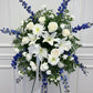 Floral arrangement with white and blue flowers on a stand against a gray background