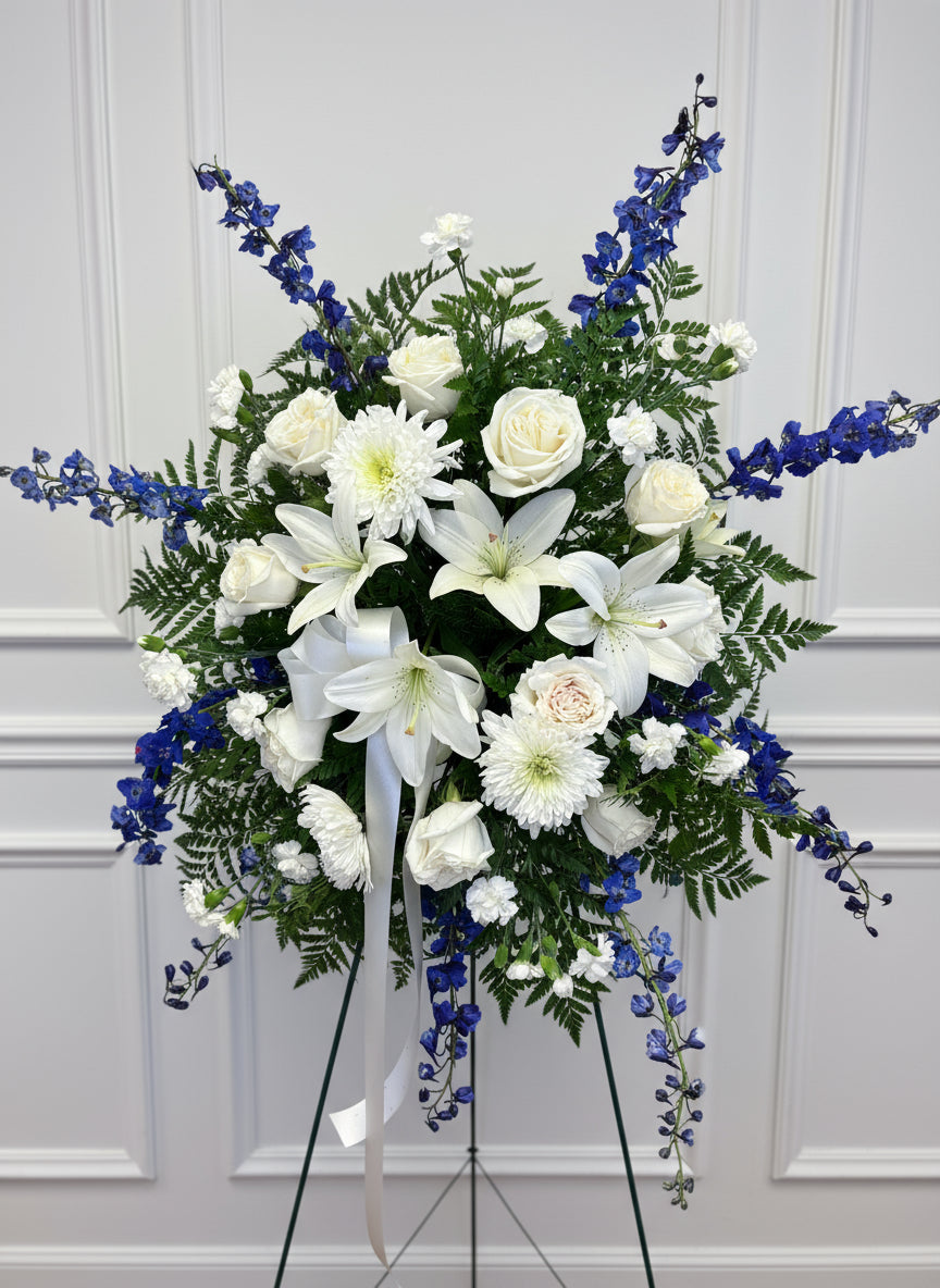 Floral arrangement with white and blue flowers on a stand against a gray background